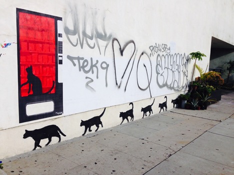 Cats painted along a wall in an alley.